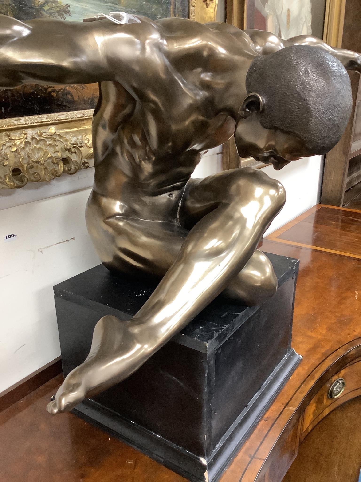 A contemporary bronzed composition figure of a seated male nude, width 138cm, height 68cm